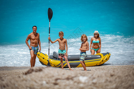 幸福的家庭站在沙滩橡皮艇附近背景图片