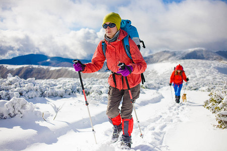 两个女孩冬天带着狗在山上旅行图片