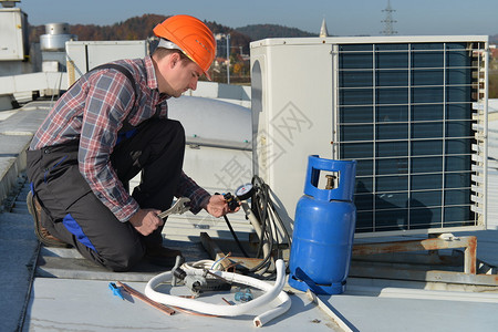 空调修理机修屋顶空调系统的年轻维修员图片