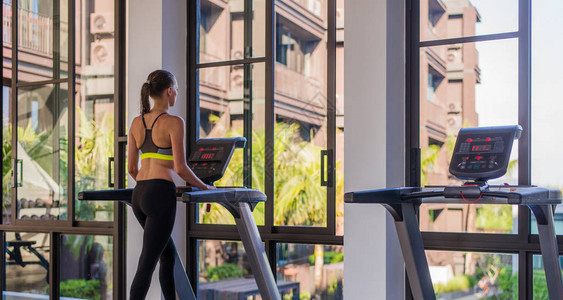 在豪华度假村的健康运动俱乐部跑步机上慢跑的女人的水平镜头图片