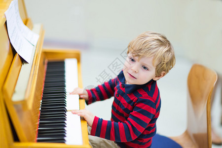 两岁快乐蹒跚学步的男孩弹钢琴幼儿的早期音乐教育孩子在学图片