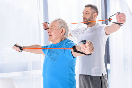 康复治疗师和老人用橡皮筋锻炼图片