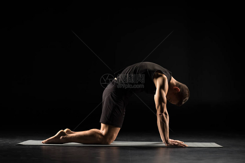 一个人在瑜伽垫上做瑜伽表演猫姿势在孤立于黑边图片