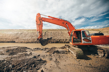 在公路建筑工地挖土工程期间工作的重型工业挖掘机图片