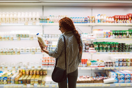 超市乳品柜前挑选牛奶的女人图片