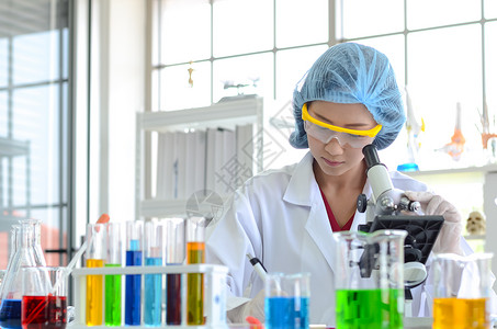 实验室里的女科学家用显微镜做实验医疗保健技术和药物研图片