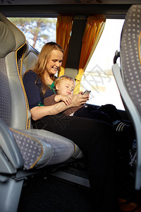 年轻母亲在乘公交车旅行时与儿子通图片