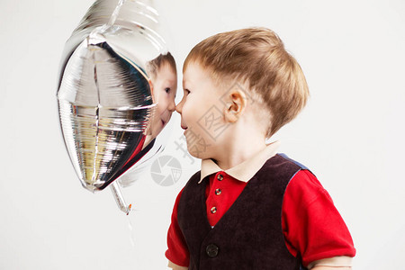 孩子看着他在箔气球中的倒影图片