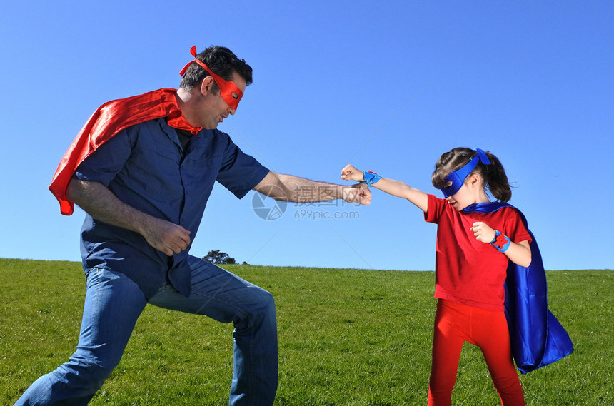 超级英雄父亲向他的女儿展示如何成为一个拥有复制空间的蓝天背景的超级英雄超级英雄童年想象力父亲身份和父母身份的概念照图片