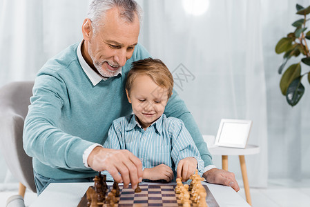 微笑的中年男子在家教孙子下棋图片