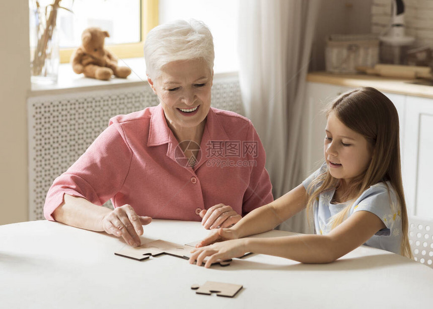老年妇女和她的孙女一起在厨房玩拼谜游戏图片