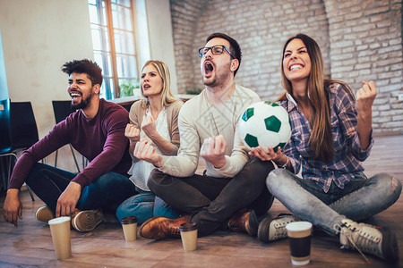 快乐的朋友或足球迷在电视上观看足球并庆祝胜利友谊体图片