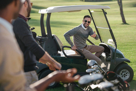 时尚的高尔夫球手坐在高尔夫球场的高尔夫球车背景图片