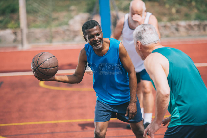 多种族老年男子在夏季日操场一起打篮球