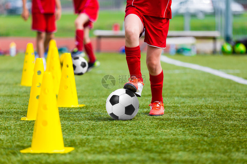 足球员在比赛前的团队训练中足球青年队的练习带球和标记锥的图片