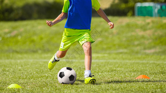年轻的足球运动员在足球场上踢球穿着运动服踢足球的男孩带足球设备的图片