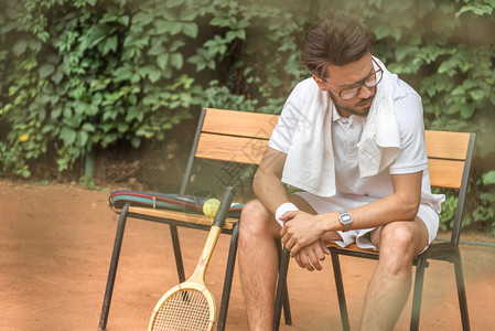 疲惫的网球运动员用毛巾和网球拍搁在网球场的椅子上图片