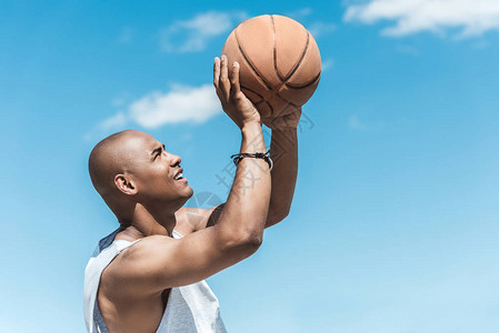 篮球运动员向蓝天投球的侧视图图片