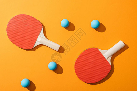 黄色乒乓球拍附近蓝色乒乓球的顶视图背景图片