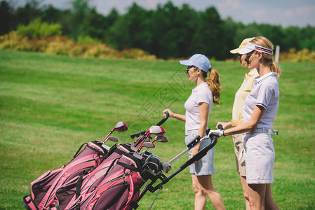 带着高尔夫设备在高尔夫球场行走的女高尔夫图片
