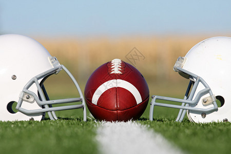 球场上的美式足球和头盔背景图片