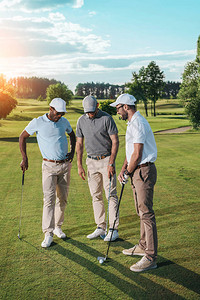 球员站立拍球多族裔高尔夫球手群体在绿色草地上站着时举行背景