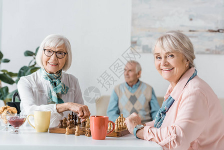 老年妇女下棋喝咖啡而老年男图片