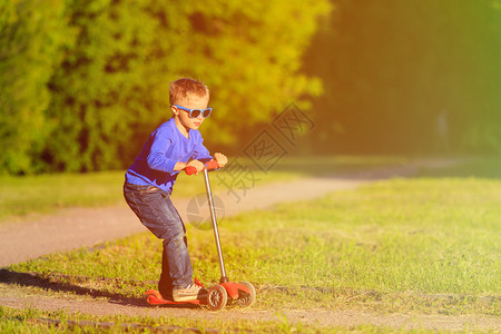 小男孩在夏日公园骑摩托图片