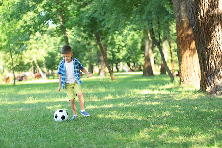 小男孩在公园踢足球图片