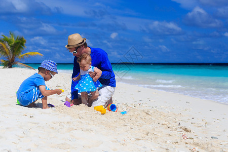 父亲和孩子在热带沙滩玩耍图片