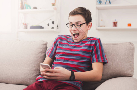 兴奋的青少年在家里移动电话上玩网上游戏成图片