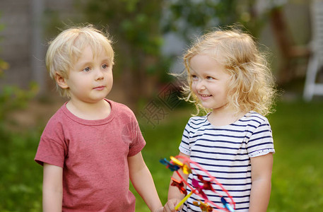 小男孩和女孩在散步时很开心快乐的孩子与风车夏季公园的学龄前儿童或图片