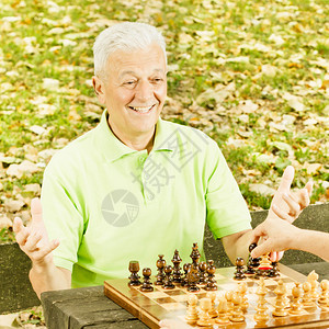 快乐的老人在公园的长椅上下棋图片
