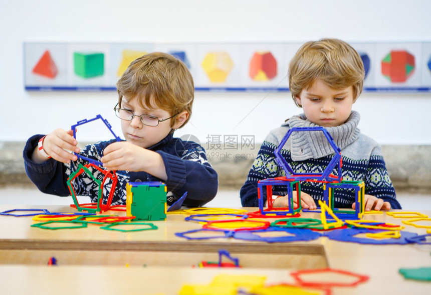 两个小孩在室内玩很多五颜六色的塑料积木套件孩子们在构建和创造几何图图片
