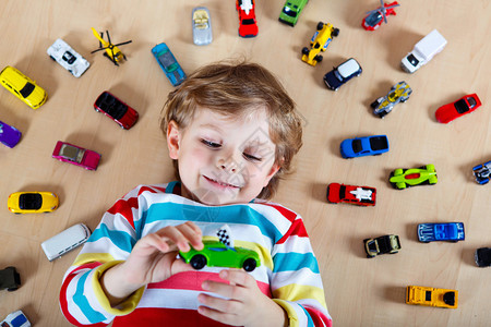 可爱的小金发孩子在室内玩具汽车游戏图片