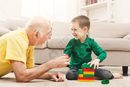 小快乐的男孩儿和他爷玩耍在多彩儿童建筑工具箱里背景图片