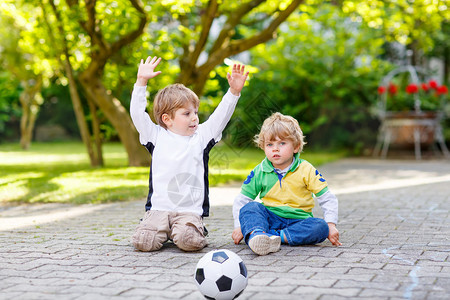 2个兄弟男孩在踢足球踢足球和户外玩乐在阳光明媚的夏日与孩子们图片