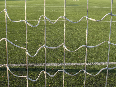 足球网中挂着的白色橄榄球网背景是足球场上涂有草图片