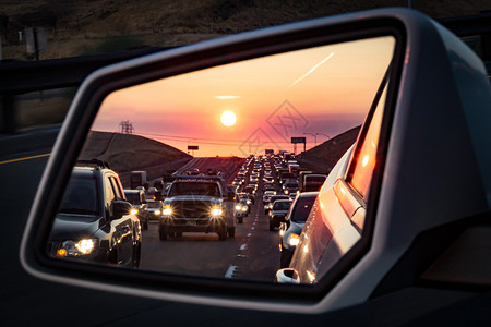 日出时后视镜中的交通拥堵和大灯背景图片