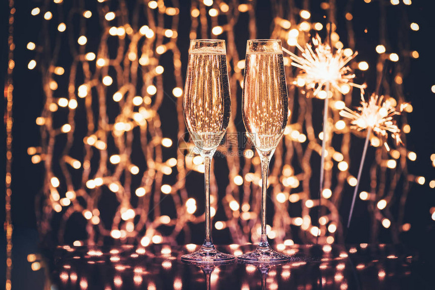 香槟和火花的玻璃杯与圣诞节灯对着圣诞灯图片
