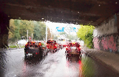 在交通繁忙的雨中驾驶汽车在驾驶汽车时通过带有雨滴的挡风玻璃图片