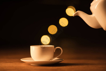 白色茶壶咖啡杯和黑色背景的bokeh灯光图片