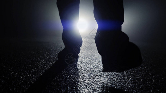 在黑暗中靠着车灯行走的人背景图片