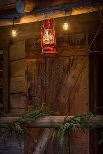 古老的红色金属和玻璃飓风雨挂在黄昏时分的铁原木小屋外图片