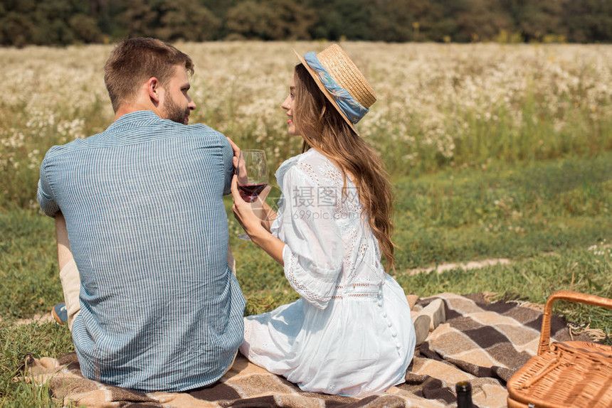 看到一对微笑的情侣在夏日草原上野餐