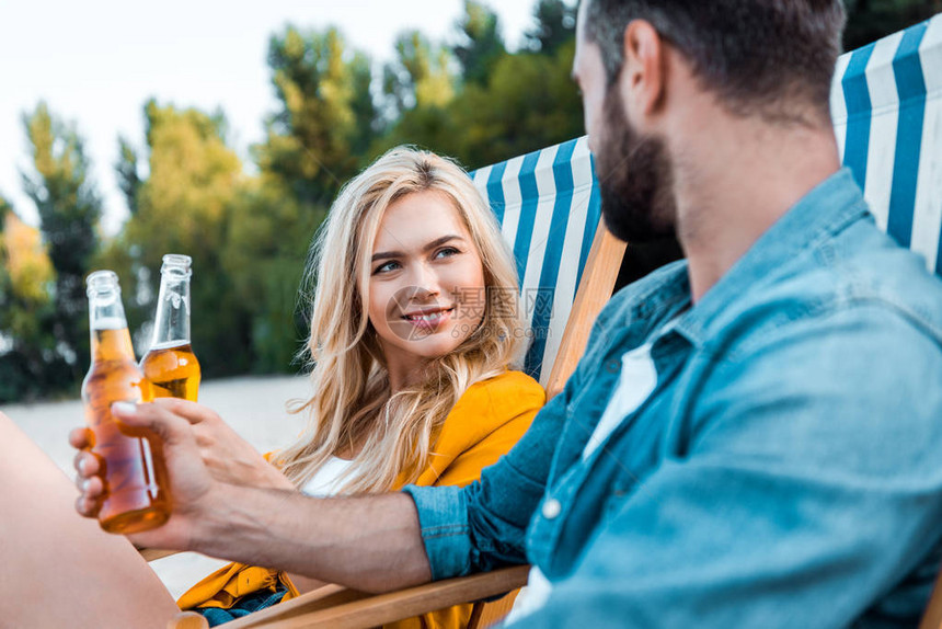 一对夫妇坐在沙滩椅上拿起酒瓶干杯图片