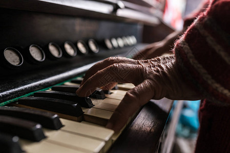 老人在玩风琴的时候近距离地看他的皱纹手在键盘上背景图片
