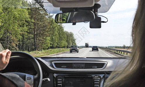 从车辆的前窗可见到一条宽阔的双向街道并沿着它行驶着汽车背景图片