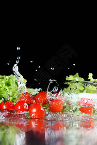 红色新鲜樱桃番茄和绿色生菜在黑色分离的水中图片