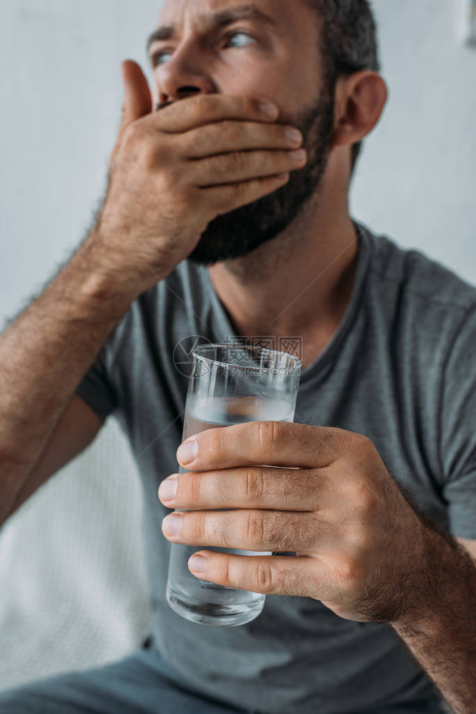 近视中留胡子的中年男子拿着水杯图片